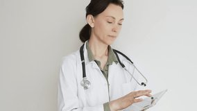 Confident doctor woman female medical professional wearing lab coat over green blouse and stethoscope is using digital tablet, representing modern healthcare and medical technology. Medicine concept - Powered by Shutterstock - Get 15% off with code: PIKWIZARD15