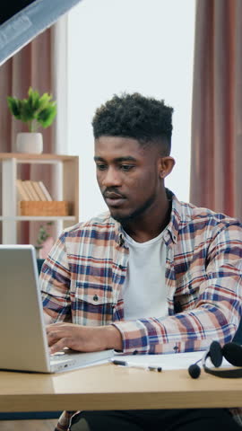 Camera shooting of likable confident modern young black-skinned male IT -worker which explaining how to use computer programms during online broadcasting for internet audience