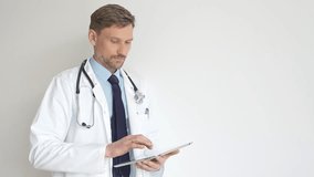 Doctor man medical professional wearing white lab coat, holding digital tablet and stethoscope, focusing on electronic patient records with advanced healthcare technology. Medicine and health care - Powered by Shutterstock - Get 15% off with code: PIKWIZARD15