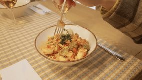 Close-up shot of a woman's hand eating seafood pasta at a restaurant table with a glass of wine during a romantic dinner - Powered by Shutterstock - Get 15% off with code: PIKWIZARD15