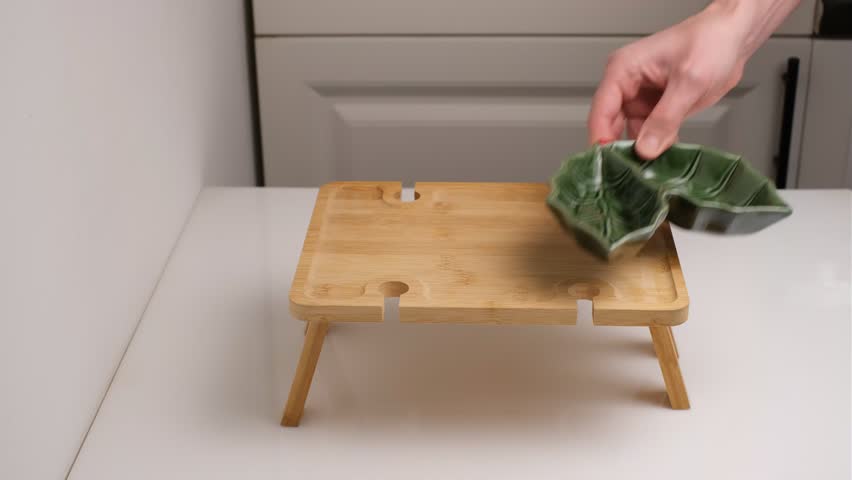 Man in kitchen arranges sauce bowls on wooden tray