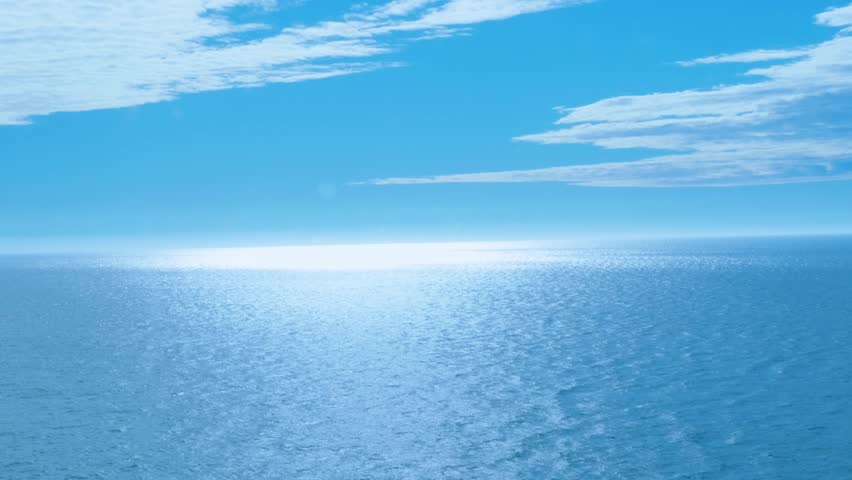 Vast ocean view under a bright blue sky with gentle clouds, reflecting sunlight on the shimmering water surface, creating a serene and tranquil scene
