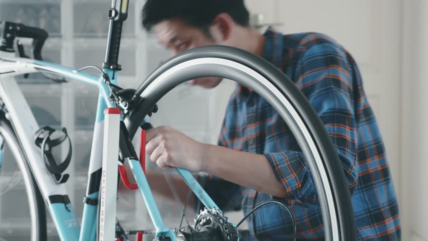 A man is sitting on the floor and fixing a bicycle. Concept of determination and focus as the man works on the bike