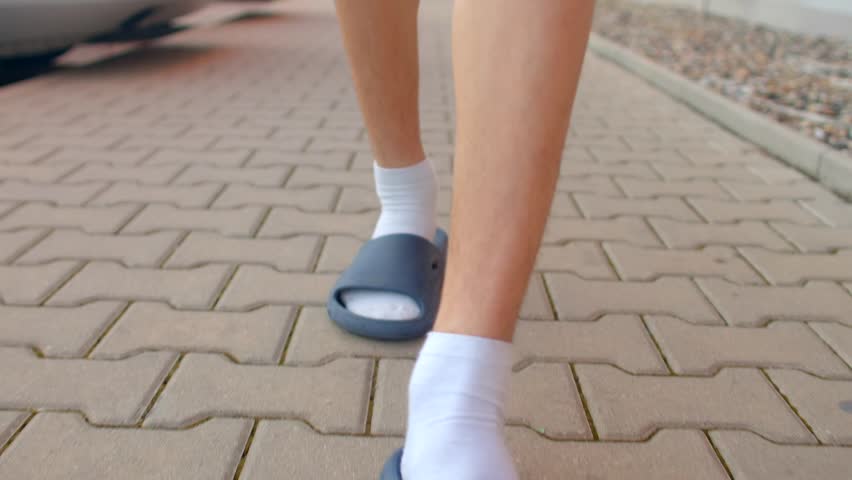 close low angle caucasian feet stepping pavement rhythmic slide and sock detail paver texture casual pace