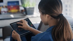 Young woman trading online using a tablet while sitting on a sofa, showcasing digital investing, finance, and modern technology lifestyle. - Powered by Shutterstock - Get 15% off with code: PIKWIZARD15