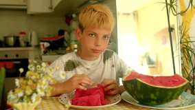 caucasian boy eating watermelon at kitchen table, bright red slices on plate, sunlight through window, juicy - Powered by Shutterstock - Get 15% off with code: PIKWIZARD15