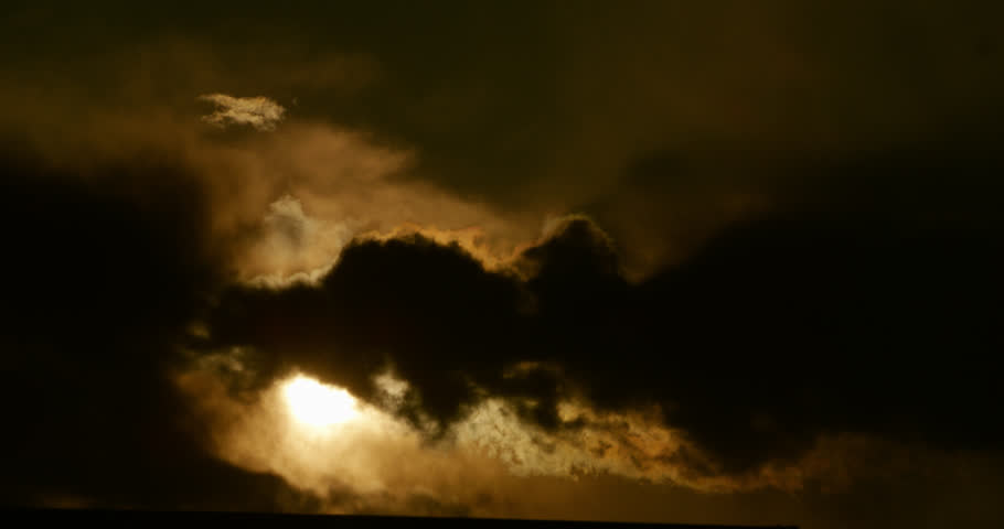 Dramatic cloudscape with rags of fractus clouds backlit by a smoldering late-day sun.