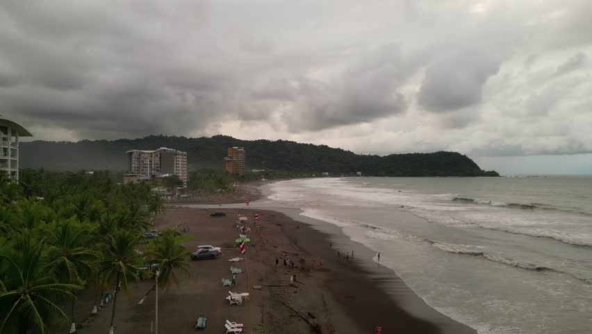 Aerial view of the coastline with waves at sunset near the beach town of Jaco with tourist and hotel buildings and businesses on Jaco Beach located in the province of Puntarenas in Costa Rica