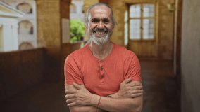Man arms crossed, smiling with visible forearms and beard in a building corridor with stone arches and sunlight; contentment resilience. - Powered by Shutterstock - Get 15% off with code: PIKWIZARD15