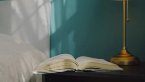 Close-Up Of Old Book Pages Turning In The Wind Beside The Bed. Cinematic View Of Soft Sunlight Touching The Pages Of An Antique Book On A Wooden Table Against A Blue Wall. - Powered by Shutterstock - Get 15% off with code: PIKWIZARD15