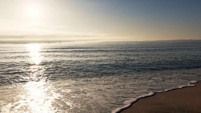 Black Sea and beach nearby against a sky with clouds and a dawn sun