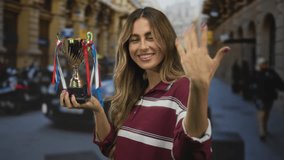 Smiling woman holds trophy in outstretched hand on busy city street; celebration achievement success joy. - Powered by Shutterstock - Get 15% off with code: PIKWIZARD15