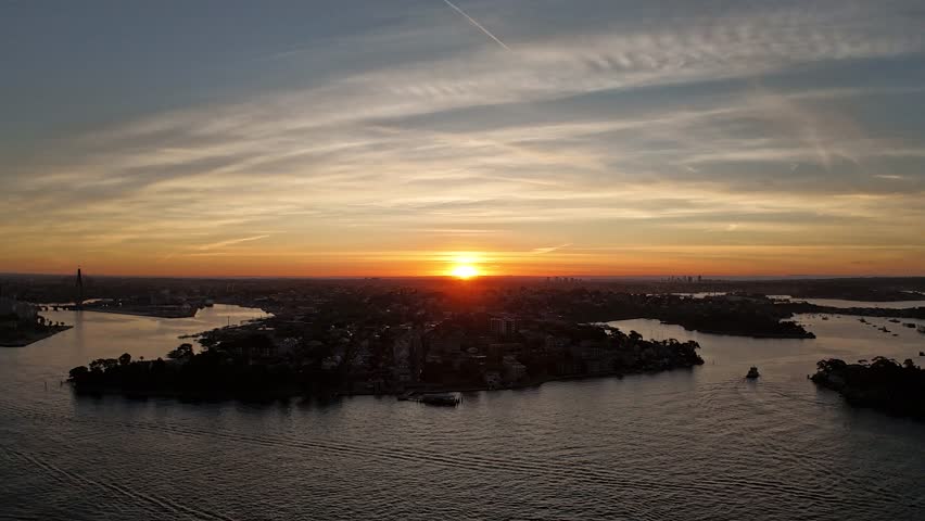 Aerial drone video of golden sunset over rocky coastline and ocean waves with dramatic clouds in the sky in New South Wales, Australia