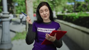 Woman volunteer writing notes in a park with a clipboard, surrounded by lush greenery, wearing a purple shirt, focused, brunette, beautiful, outdoors, suggesting an engaged moment. - Powered by Shutterstock - Get 15% off with code: PIKWIZARD15