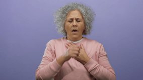 Woman coughing on purple background with grey hair in pink sweater, middle-aged, isolated indoors, expressing illness or discomfort in bright casual setting. - Powered by Shutterstock - Get 15% off with code: PIKWIZARD15