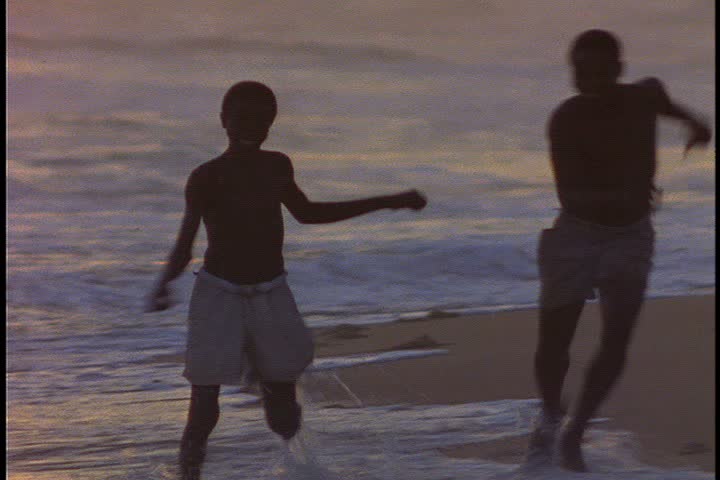  MS of two boys running and playing around as they run in the wet sand at water