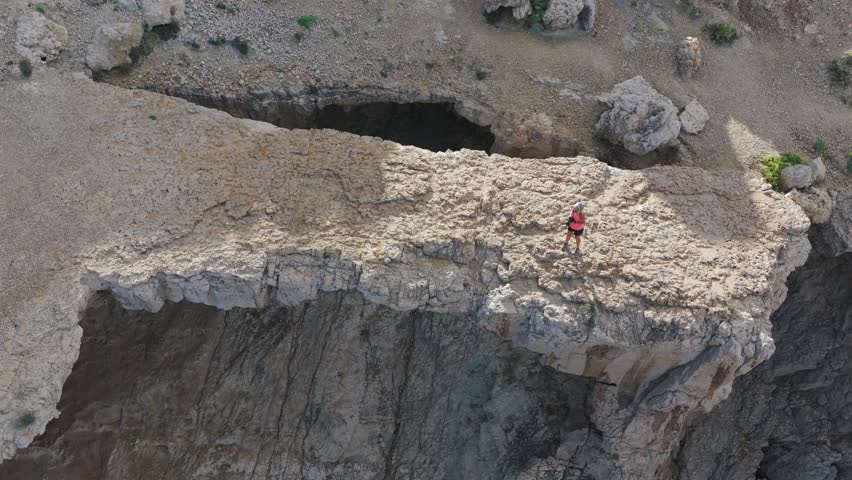Adventurous Female Hiker Crossing the Dramatic Natural Stone Bridge at Cala d'Albarca in Wild Northern Ibiza