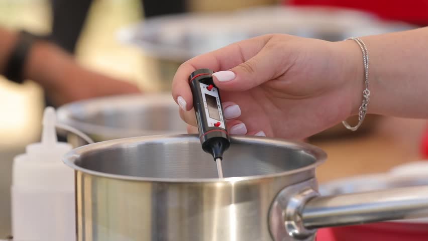 A person accurately measures liquid temperature with a digital thermometer in a stainless steel pot. This precise method is crucial for cooking and baking, ensuring perfect results and food safety in 