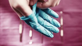 A medical professional puts on blue latex gloves to prepare for a procedure, with dental tools blurred in the background - Powered by Shutterstock - Get 15% off with code: PIKWIZARD15