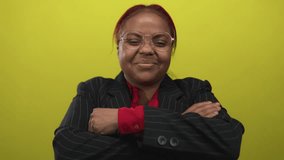 Woman crosses arms with glasses and smirk in studio with yellow backdrop; confidence empowerment pride achievement success motivation ambition optimism inspiration selfesteem. - Powered by Shutterstock - Get 15% off with code: PIKWIZARD15