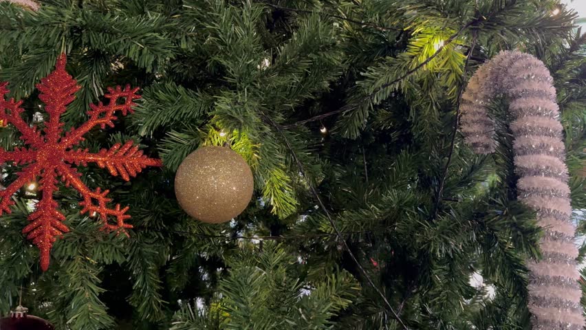 Close-up detail of a Christmas tree with decorations such as candy canes, snowflakes, lights and balls.