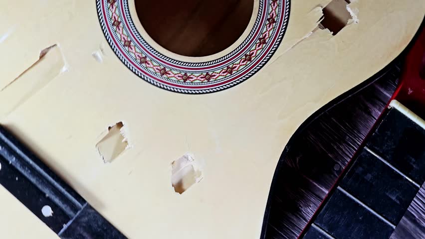 A broken wooden old classic guitar with damaged strings chords, shattered musical instrument, unattached damaged guitar with cut chord and wood, selective focus of non working music instrument