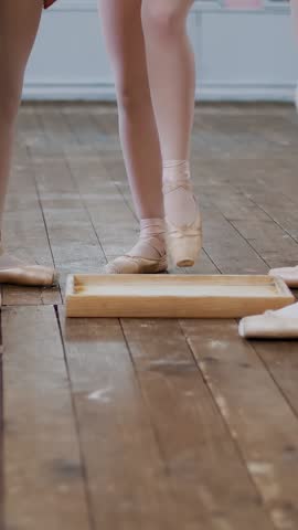 Close-up, the feet of young dancers, the girls lower the tips of the pointe shoes into a box with special powder.