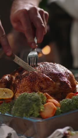 Vertical slow motion video carving roasted turkey on festive table with vegetables holiday dinner celebration thanksgiving or christmas family feast cozy atmosphere warm light joyful evening