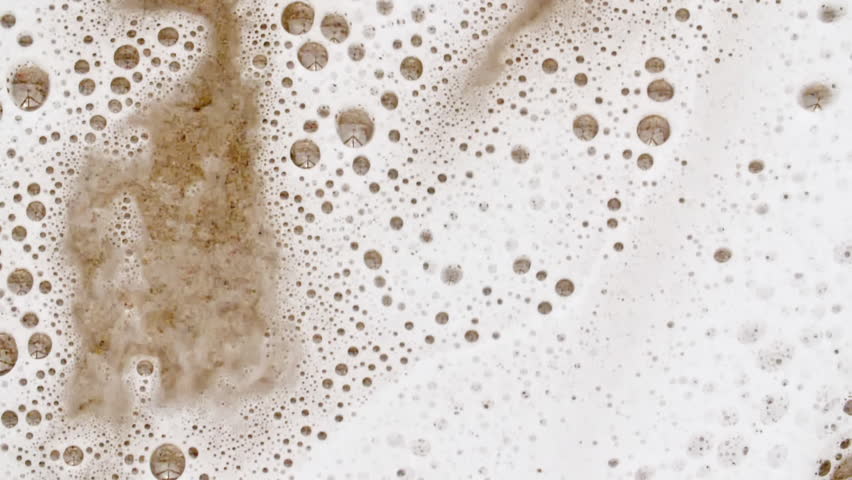 Waves of White Soapy Foam Flowing Down the Yellow Surface. Texture of Bubbles on abstract background. Soap sud macro structure. Bathtup Soap Foam. Natural White Shampoo Bubbles Motion.