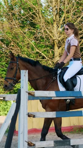 Girl rider, jockey riding on a thoroughbred beautiful brown stallion, horse, on the training ground. summer, outdoors