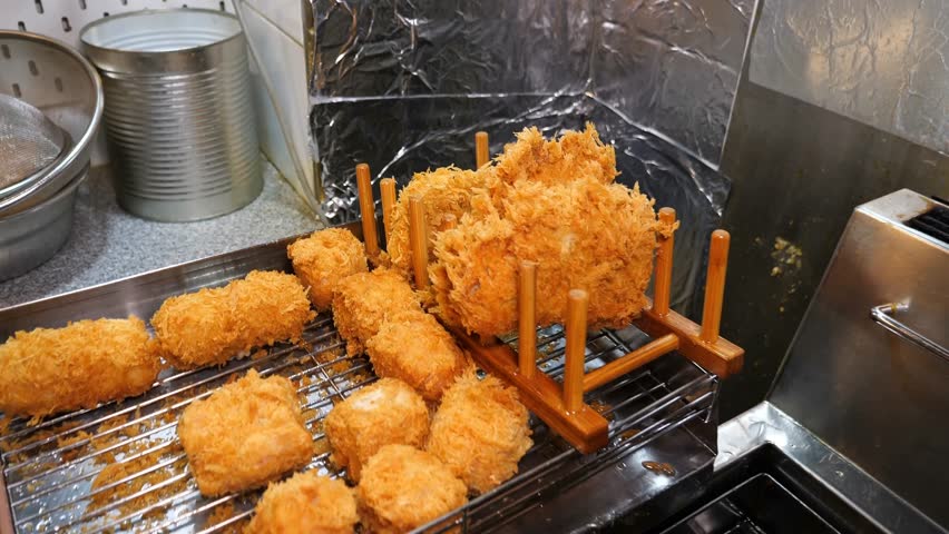 A chef in black gloves meticulously prepares two plates of spaghetti pasta with clams and garlic then garnishes each dish with crisp fried cutlets of meat and fresh microgreens