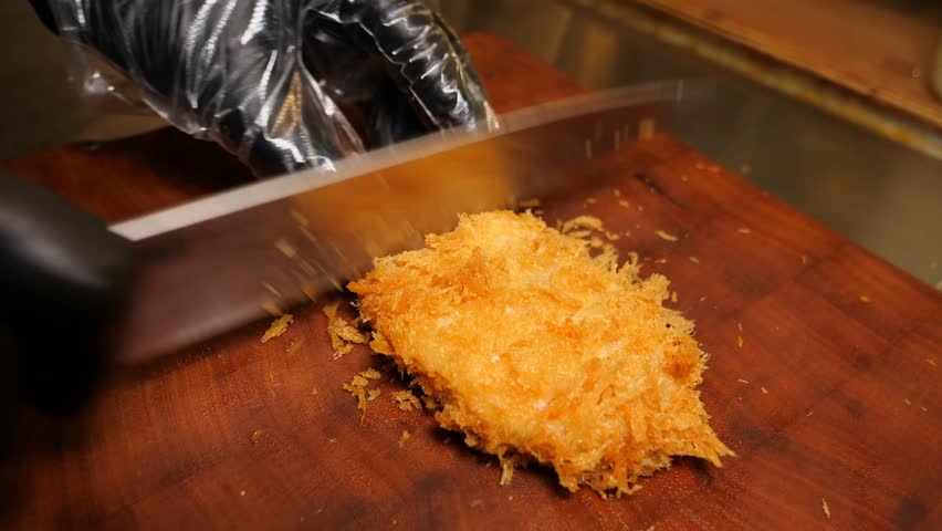 A chef arranges creamy spaghetti with large prawns and mussels onto two white plates and adds fresh green garnish and sprinkled cheese