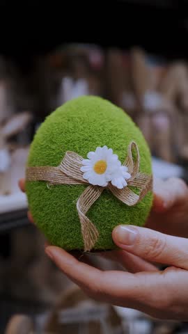 Easter fair. close-up. female hands holding a figurine of a funny green Easter egg. traditional european easter decor and decorations. Easter shopping, display in a store.
