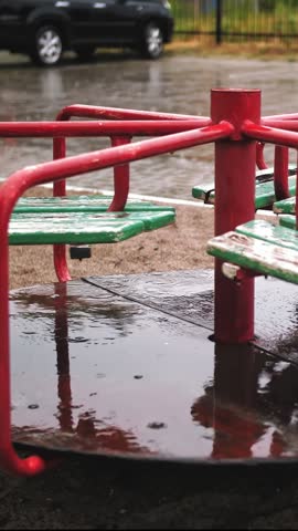 Raining on playground. close-up. Wet, empty merry go round carousel , in the yard, during heavy rain.