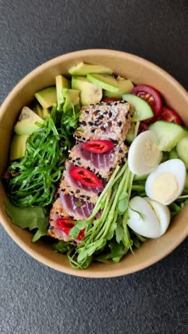 Seafood bowl, tuna tataki fillet slices with rice, oranges, tomatoes and sauce. Tuna bowl as a food background for your design