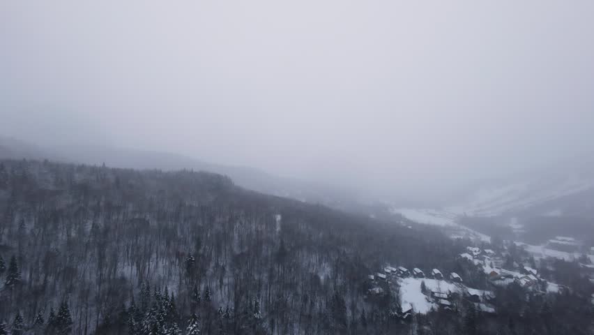 FPV flight above a winter road gradually disappearing into falling snow and fog.