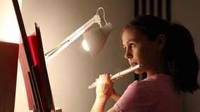 A teenage girl plays the flute in a dark room - Powered by Shutterstock - Get 15% off with code: PIKWIZARD15