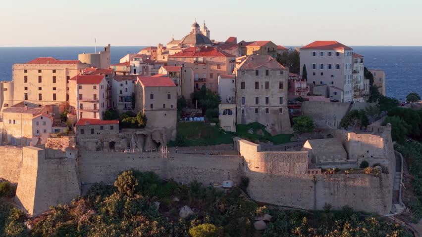 Aerial view of calvi citadel at sunrise with serene waters. Fortress with marina. Corsica. France