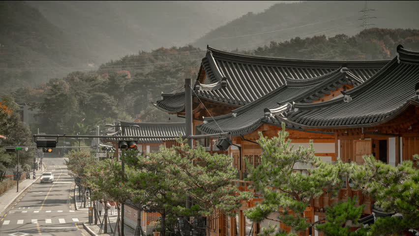 Timelapse of traditional Hanok village street with tiled rooftops and mountain background in South Korea