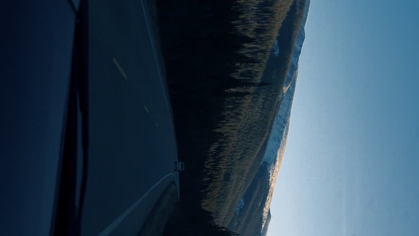 POV of a quiet winding mountain road at dusk, with a lone van driving ahead between dark trees and snowy slopes. - Powered by Shutterstock - Get 15% off with code: PIKWIZARD15