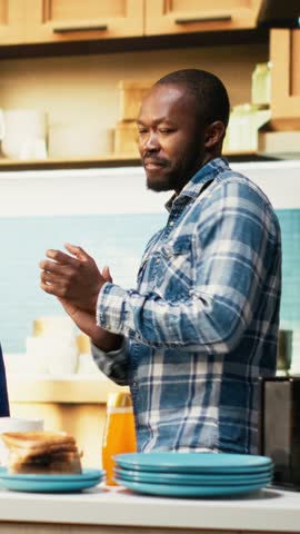 Vertical Video Boyfriend and girlfriend dancing indoors to upbeat music in the kitchen, making coffee and fooling around with silly enthusiastic energy. Playful couple show passion in comfortable home