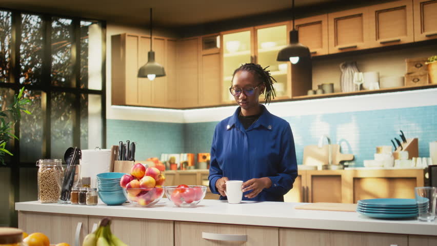 Happy adult in the kitchen smelling the fresh aroma of roasted coffee, serving delicious homemade breakfast. Woman uses prepare slices of toast with croissants and enjoys warm coffee cup. Camera A.