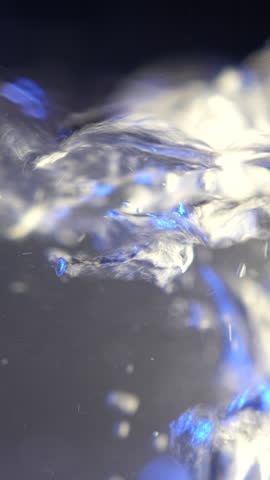 A macro close up of boiling water with rising bubbles and swirling liquid motion. The blue-toned scene highlights heat, turbulence, and fluid dynamics in a detailed abstract view.