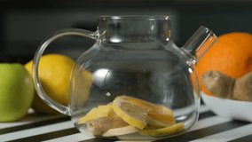 Hot water being poured into a glass teapot filled with lemon slices and ginger pieces, making a healthy detox tea for immune support and wellness concept - Powered by Shutterstock - Get 15% off with code: PIKWIZARD15