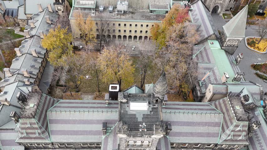 Cinematic shot pulls out from the top of the University College building at the University of Toronto, tilting the camera upward to reveal the full historic Romanesque facade and main entrance