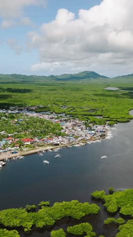 Clustered houses along the river with boats near mangrove landscape. Del Carmen. Siargao, Philippines.