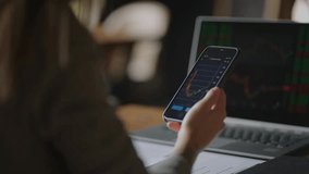 An Asian woman checks stock and cryptocurrency prices on her smartphone, analyzing real-time financial charts and market data in a modern digital investing environment. - Powered by Shutterstock - Get 15% off with code: PIKWIZARD15