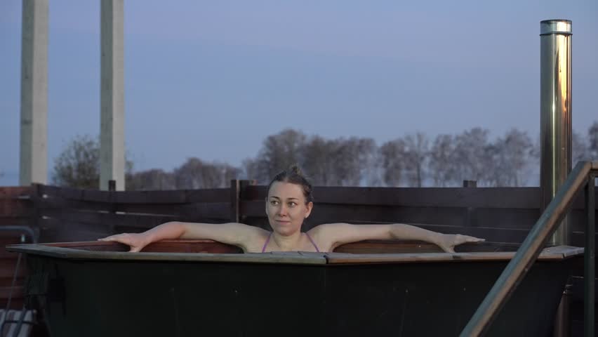 Evening bath serenity, peaceful evening spent in bubbling hot water, homeowner unwinding during tranquil twilight soak outside, calm night scene where woman enjoys soothing bath beneath evening sky
