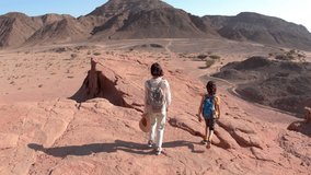 A boy and his mother are walking in the desert. The child is actively spending time. Summer vacation. Family hike. Timna National Park. Trekking and hiking. - Powered by Shutterstock - Get 15% off with code: PIKWIZARD15