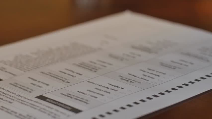 A closeup of an African American woman’s hand marking a voter ballot during a general election, symbolizing civic duty, democratic participation, and responsible voting.